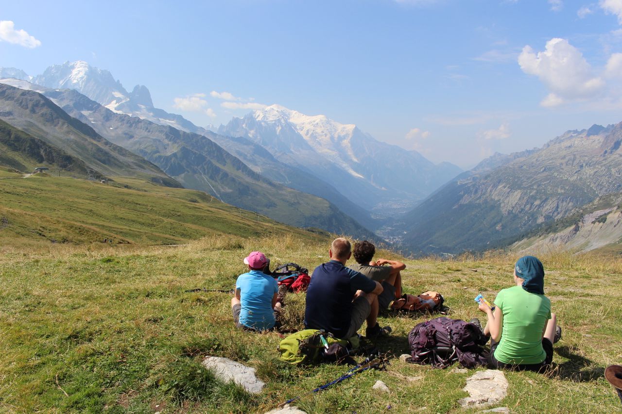 Hikers resting and enjoying a breathtaking view of alpine mountains.